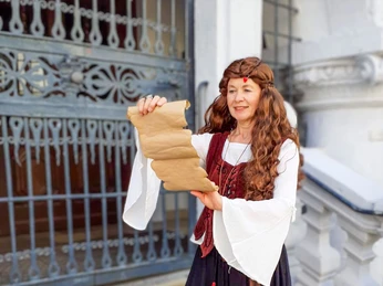 Stadtführung „Auf den Spuren der Hexen“ in Celle Gästeführerin in Kostüm liest Pergamentrolle vor dem alten Rathaus in Celle