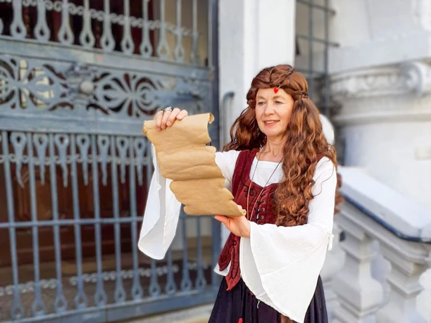 Stadtführung „Auf den Spuren der Hexen“ in Celle Gästeführerin in Kostüm liest Pergamentrolle vor dem alten Rathaus in Celle
