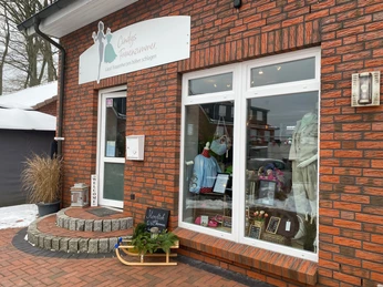 Cindys-frauenzimmer-bispingen-außenansicht.jpg Eingang eines Modegeschäfts mit Schaufenster, Kleidung, Dekoration und winterlicher Außendeko.