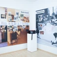 Ausstellungsraum im ZADIK Ausstellungsraum mit zwei bebilderten Wandtafeln und einem Podest mit Tasche.Exhibition room with two illustrated wall panels and a pedestal with bag.