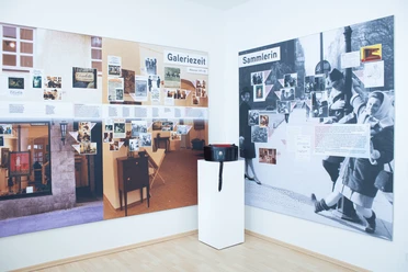 Exhibition room at ZADIK Exhibition room with two illustrated wall panels and a pedestal with bag.
