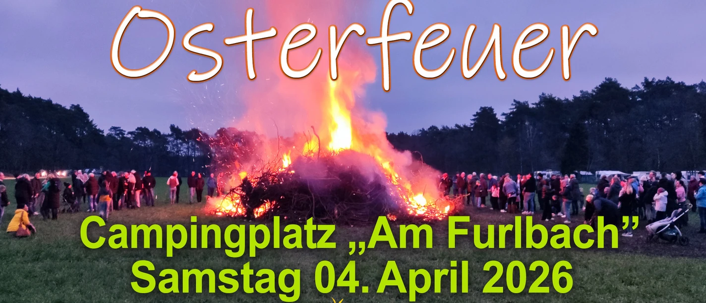 CampingplAmFurlbach_Osterfeuer 2026_1920x1080 px.jpg Großes Osterfeuer auf einer Wiese, Flammen leuchten, viele Menschen stehen im Kreis bei Dämmerung