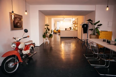 Eingang modern eingerichteter, langer Raum mit Tisch und Stühlen im Vordergrund und Loungemöbeln im Hintergrund