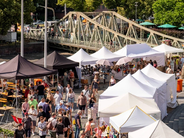Midsummer festival at the Cologne Chocolate Museum Market stalls and lots of people in front of a steel bridge at a sunny midsummer festival