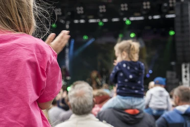 Der Familientag in Büsum Eine Menschenmenge vor einer Bühne. Zwei Kinder auf den Schultern von Erwachsenen von hinten.
