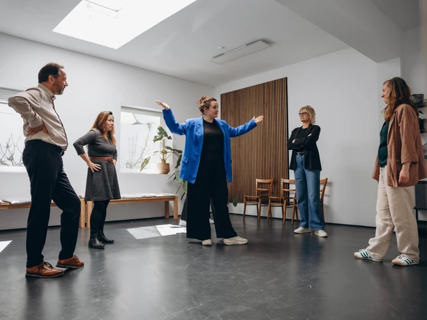 Teambuilding Improtheater Workshop mit Personen, die sich in einem Seminarraum im Kreis gegenüberstehen