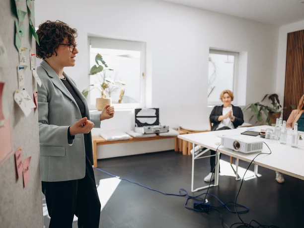 Female-Leadership-Workshop Person gives lecture to two people sitting at the table