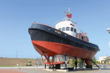 Stier_Wolfhard_Scheer (c) Wolfhard Scheer_DSM_WEB.jpg Historischer Schlepper Stier aufgebockt am Museumshafen Bremerhaven unter blauem Himmel.