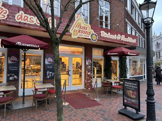 baeckerei-musswessels-Leer-Brunnenstr.jpg Eingang der Bäckerei Musswessels mit festlicher Dekoration, Außentischen und rotem Vordach in Leer.