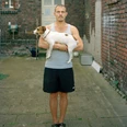 Alexander Lackmann: Ulvi, from the series "Ganz ehrlich", 2022 A man holds a small dog in the courtyard between old brick walls
