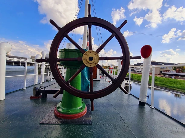 Großes hölzernes Steuerrad auf dem Deck des Museumsschiffes Rau IX im Hafen von Bremerhaven.