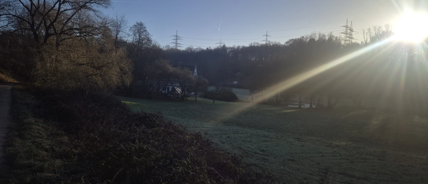 Durch die Hildener Heide, Ittertal und Stadtwald Sonniger Morgen über einer weiten Landschaft in Hilden, mit Feldern, bewaldeten Hügeln und Strommasten.