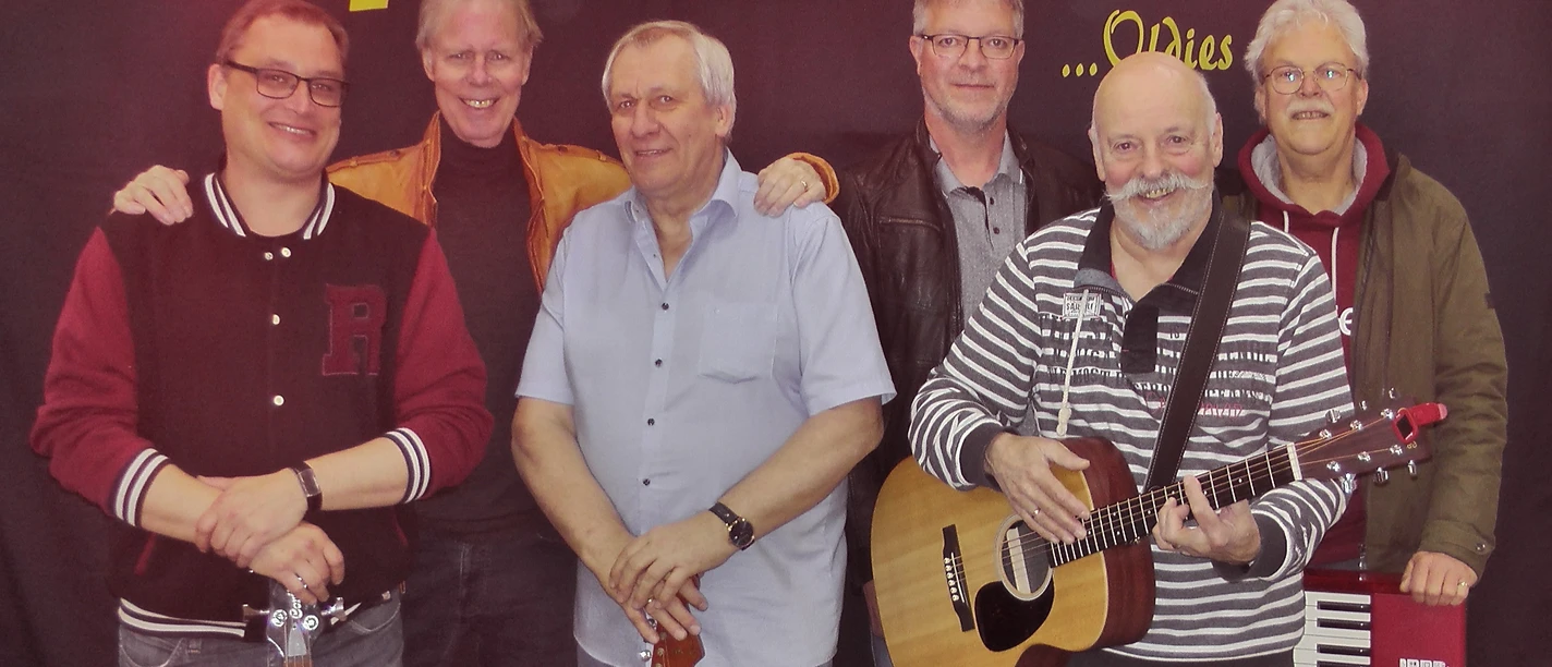 Feedback.JPG Sechs Männer stehen vor einer Wand mit dem Schriftzug 'Feedback', zwei halten Gitarren, einer steht vor einem Keyboard.