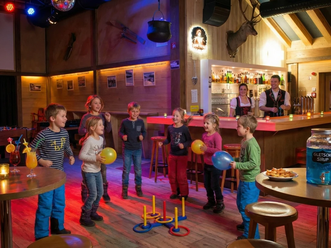 Happy dance atmosphere at the children's bar Fröhliche Kinder tanzen bei der Kinderdisco im Hotel Alpfrieden mit Ballons vor einer rustikalen Holzbar.Cheerful children dance with balloons in front of a rustic wooden bar at the children's disco in the Hotel Alpfrieden.Des enfants joyeux dansent avec des ballons devant un bar en bois rustique lors de la disco pour enfants à l'hôtel Alpfrieden.