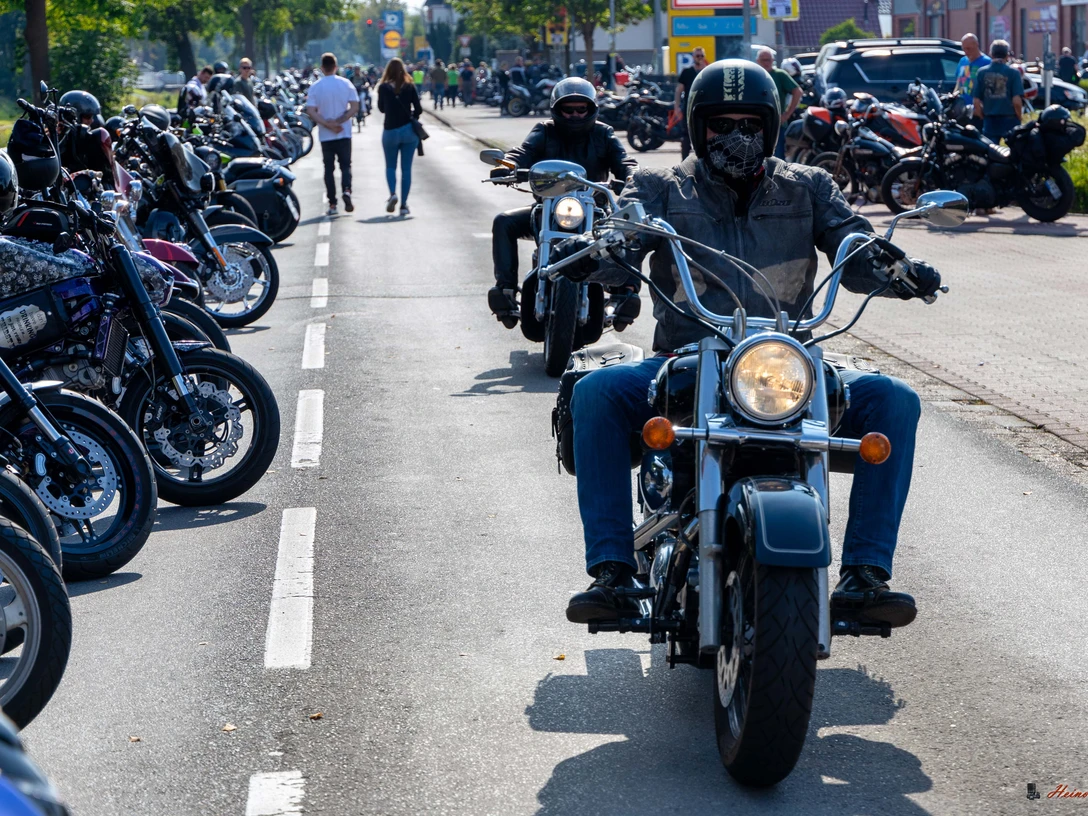 Motorräder bei Börjes_Heino Fecht.jpg Motorradfahrer auf einer belebten Straße beim Herbsttreff in Augustfehn, umgeben von geparkten Bikes.