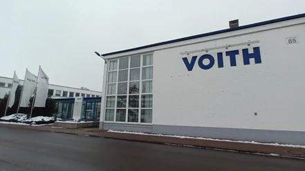 2026_Betriebsbesichtigung_Voith (2)_HD_16zu9.jpg Eingangsbereich des Voith-Werks in Salzgitter mit Firmenlogo und wehenden Fahnen an einem Wintertag