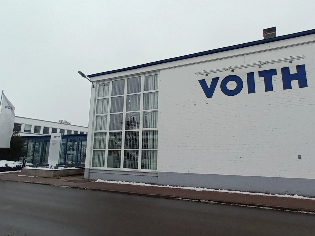 2026_Betriebsbesichtigung_Voith (2)_HD_16zu9.jpg Eingangsbereich des Voith-Werks in Salzgitter mit Firmenlogo und wehenden Fahnen an einem Wintertag