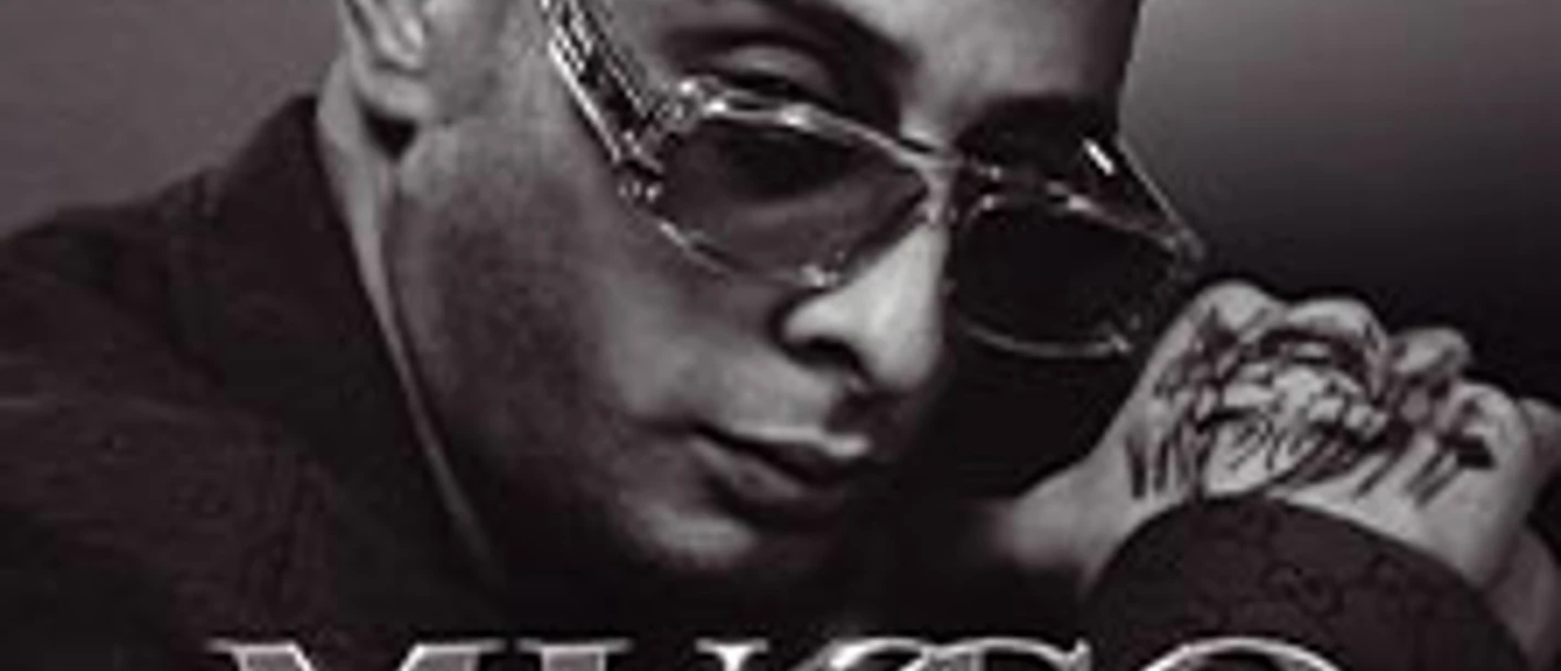 Porträt eines Mannes mit Sonnenbrille und Handtattoo vor dunklem Hintergrund.