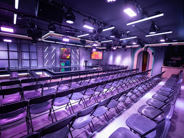 Der Club von innen lila beleuchteter Club mit Bühne und Stuhlreihen