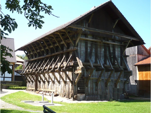 Saline Sülbeck Historisches Gradierwerk aus Holz mit markanten Stützbalken auf einer gepflegten Wiese.