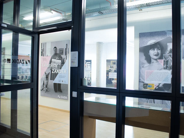 Exhibition room at ZADIK Entrance to the exhibition with posters and large-format photographs behind glass.