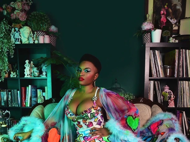 Zyra Lee Vanity Person in a colorful burlesque outfit sits in an opulently decorated room.