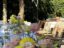 Blumengesteck auf gedeckter Terrasse mit Sonnenschirmen und Sitzplätzen im Grünen