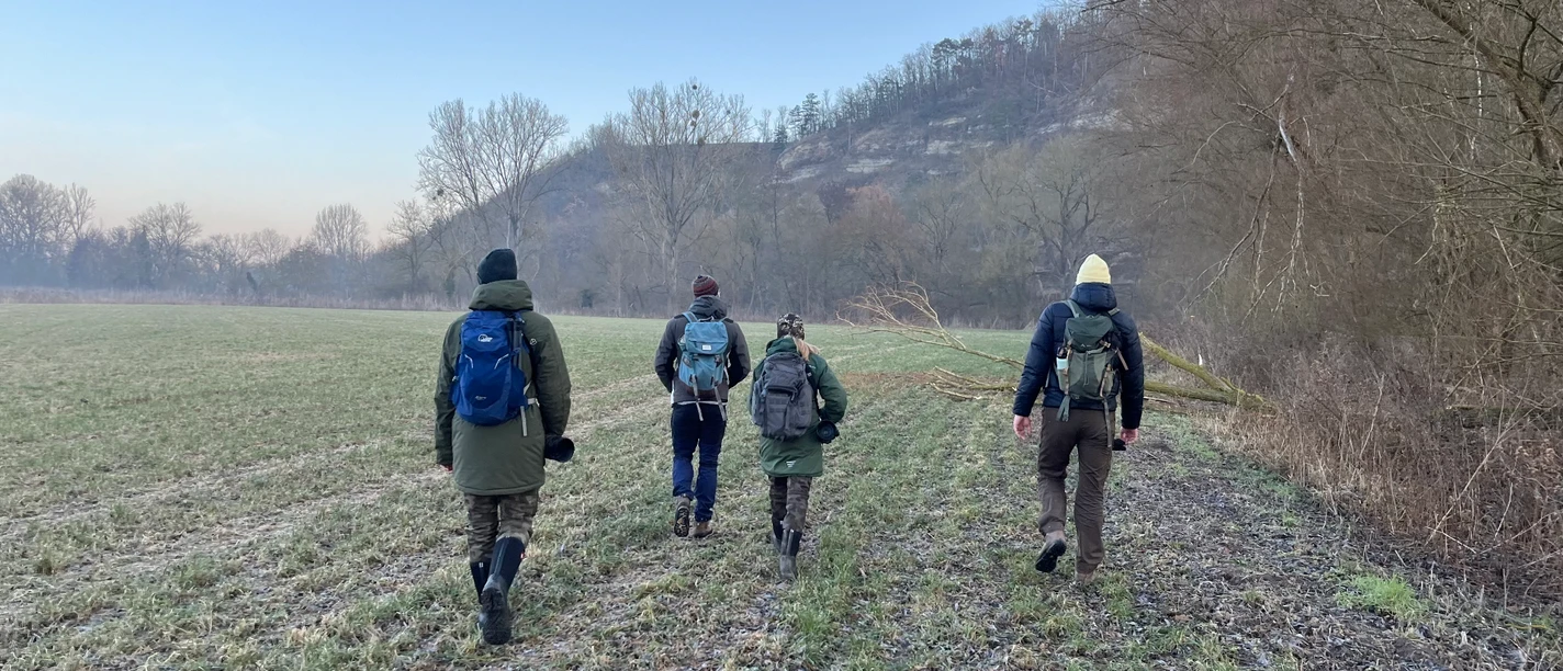 Menschen gehen entlang der Saale ein Feld entlang