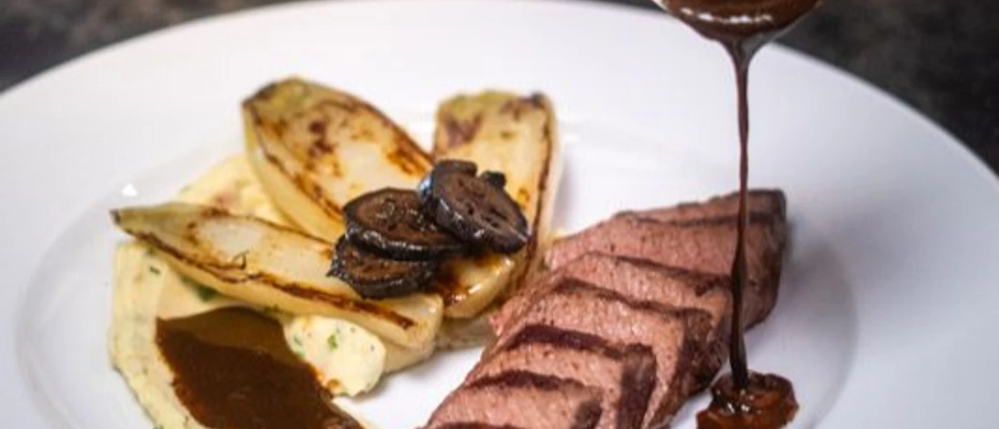 Brasserie 27 chez Marc (c) AGC Gastro GmbH.jpg Auf einem weißen Teller wir Bratensoße auf Rinderfiletstreifen und Pak Choi geträufelt.