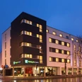 Holiday Inn Express Gütersloh Modernes Holiday Inn Express Hotel in Gütersloh bei Dämmerung, Eckgebäude mit beleuchteten Fenstern