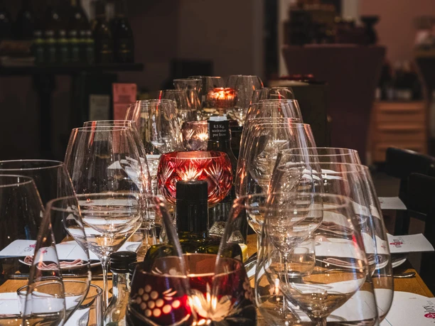 Easy tasting at the wine&glory Kiosque Table with many wine glasses, red lanterns and bottles in warm light.