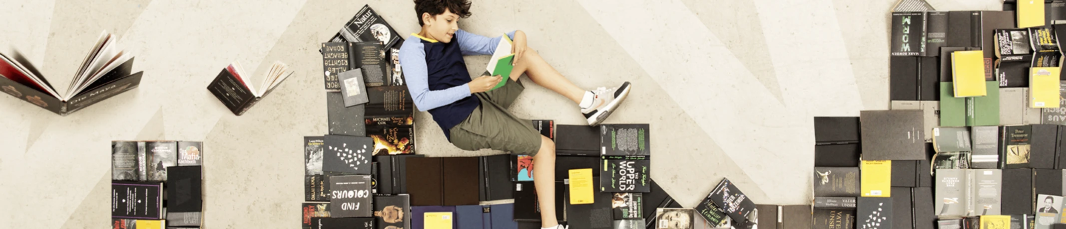 Vorlesewettbewerb Kreisentscheid Kind liest vertieft auf Bücherstapeln, umgeben von offenen Büchern, Atmosphäre eines Lesewettbewerbs