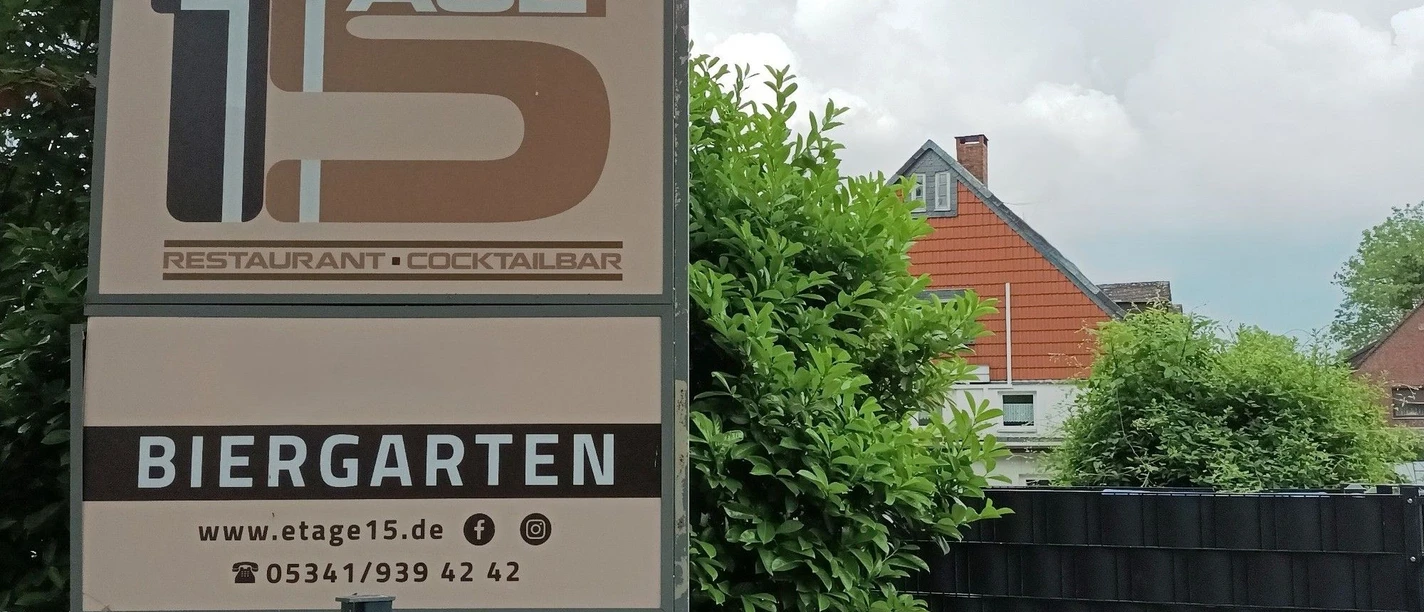Außenschild von Etage 15 mit Restaurant- und Biergartenhinweis vor Wohnhäusern