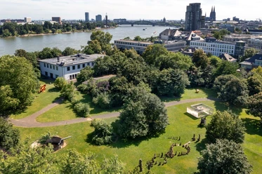 Skulpturenpark Köln Luftaufnahme eines grünen Parks mit Skulpturen am Rhein vor urbaner Kulisse in Köln