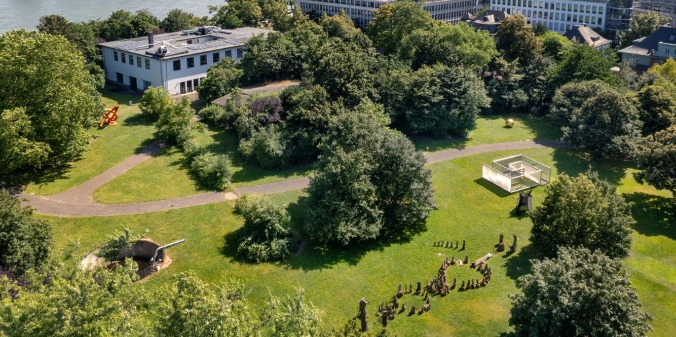 Skulpturenpark Köln Luftaufnahme eines grünen Parks mit Skulpturen am Rhein vor urbaner Kulisse in Köln