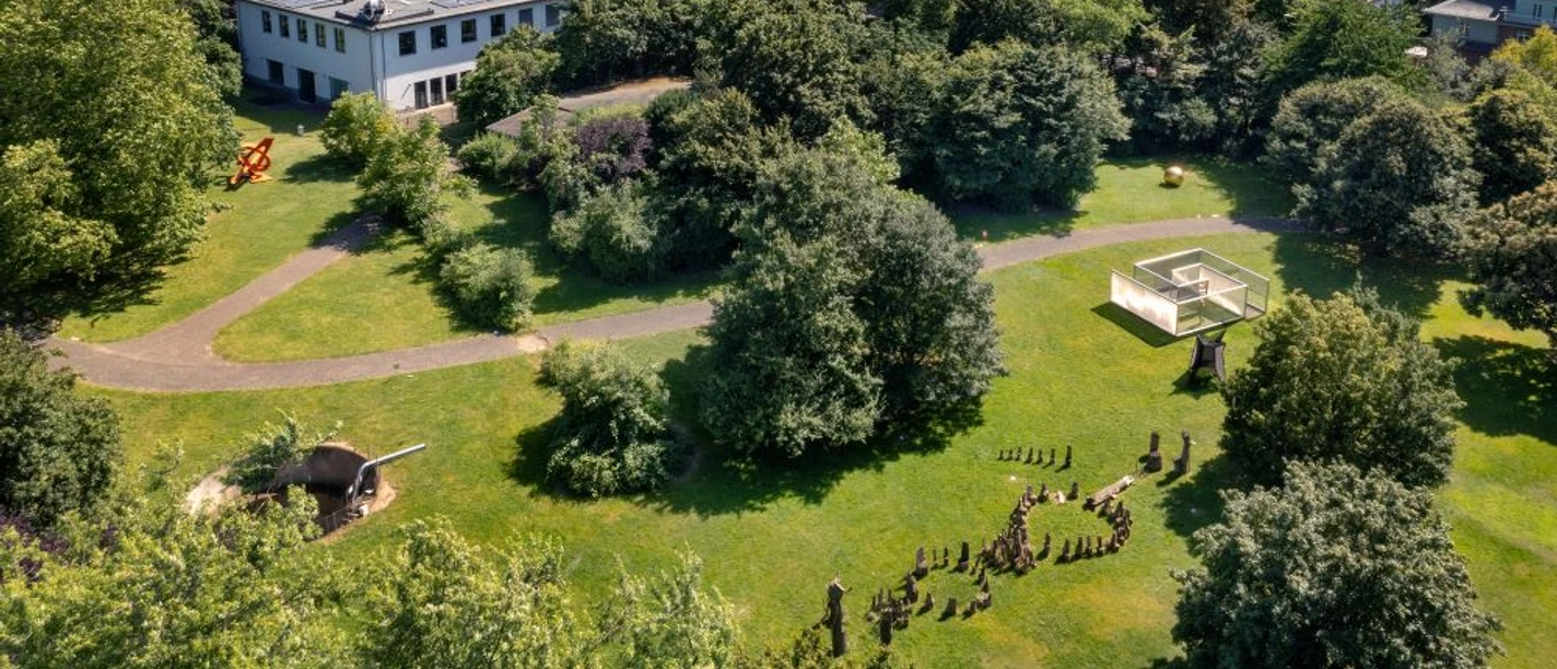 Skulpturenpark Köln Luftaufnahme eines grünen Parks mit Skulpturen am Rhein vor urbaner Kulisse in Köln