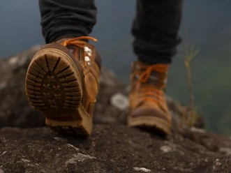 Wanderer Tiefwinkelaufnahme von Wanderstiefeln auf Fels beim Biwakieren in der Natur