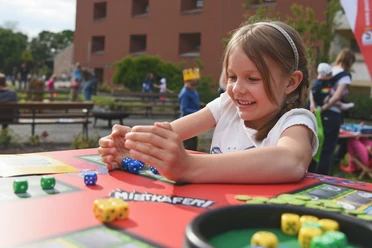 maedchen-spieltisch-1920x1280.jpg Ein Mädchen spielt mit Würfeln an einen Spieltisch im Garten