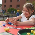 maedchen-spieltisch-1920x1280.jpg Ein Mädchen spielt mit Würfeln an einen Spieltisch im Garten