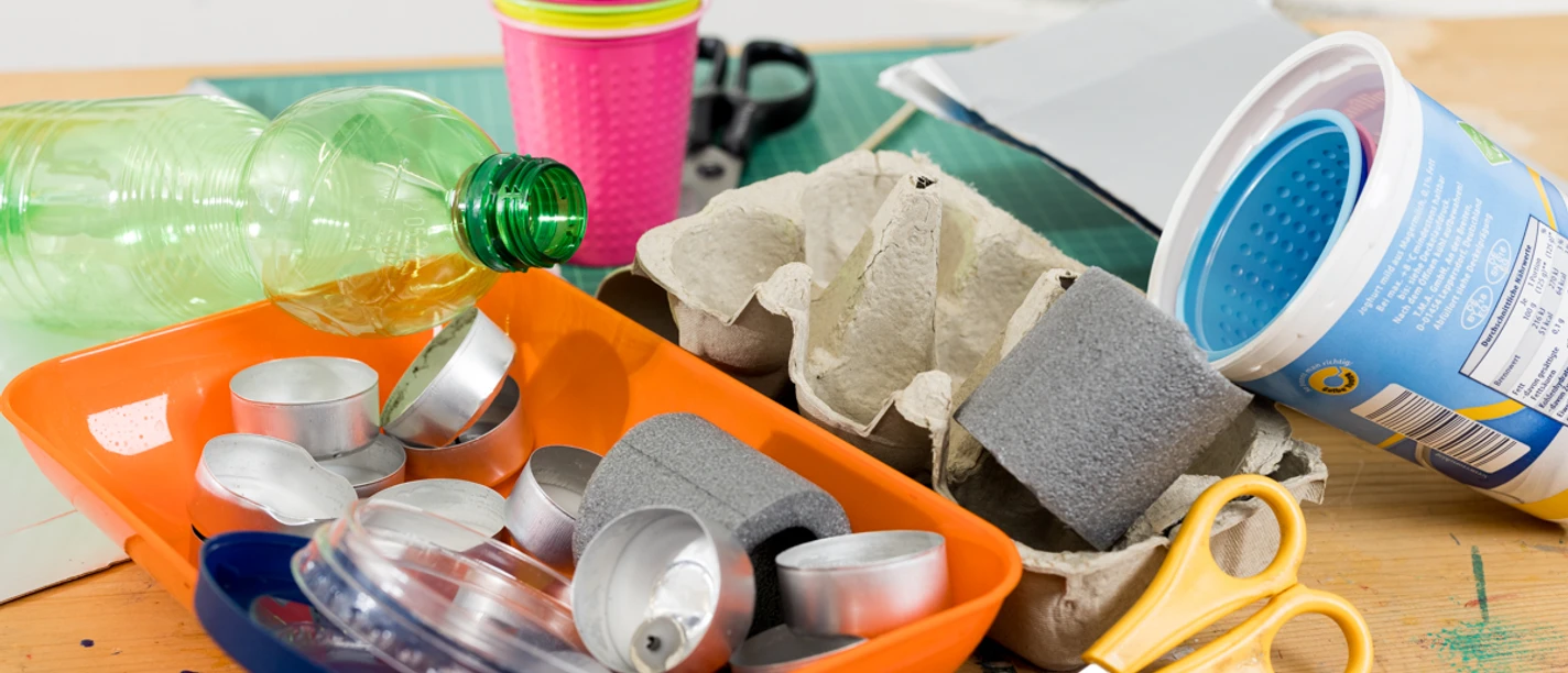 Arbeitsgerät Arbeitsmaterialien für eine Ferienaktion: Flaschen, Becher, Scheren, Eierkarton und Teelichtschalen.