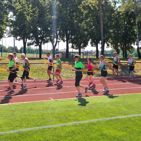 Lauf ABC.jpg Gruppe von Menschen macht Lauf ABC auf einer Laufbahn im Stadion.