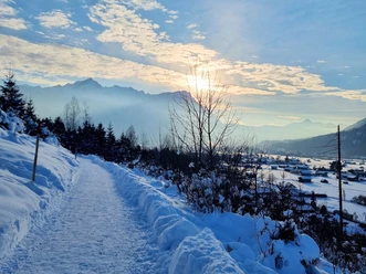 Philosophenweg in Richtung Garmisch-Partenkirchen Verschneiter Weg mit Blick auf Berge und tiefstehende Sonne über einem Wintertal