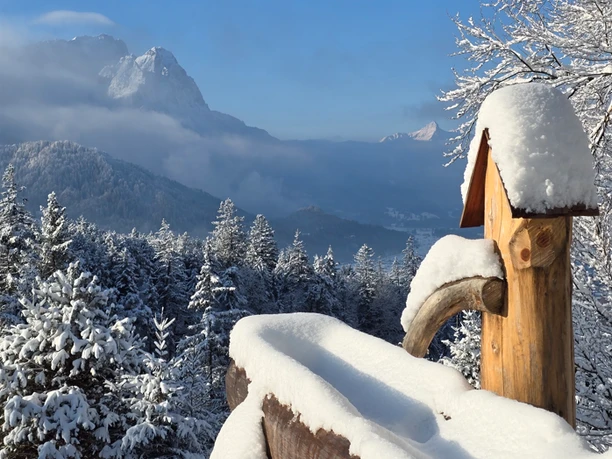 Winterwanderung zur Tannenhütte Verschneite Berglandschaft mit einem hölzernen Brunnen vor schneebedeckten Fichten