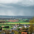 Wiehengebirge Blick über Dorf, Felder und Windräder unter dunklen Regenwolken