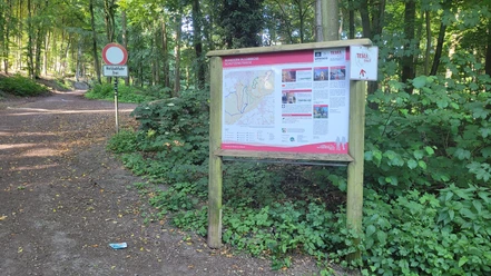 Wanderparkplatz "Schütztenstraße" Infotafel am Wanderparkplatz im Wald, daneben breiter Forstweg und Verkehrsschild