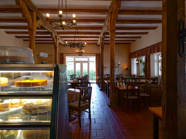 Kutscherscheune in Gut Groß Zecher Bright room for dining with wooden posts and cake container at the front.