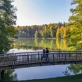 Wandern am Schmalsee Zwei Menschen laufen auf einer Brücke über den Schmalsee bei Mölln. Die umgebenden bäume strahlen in bunten Herbstfarben.