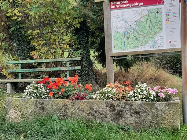 Wanderparkplatz Am Walde mit Infotafel, Bank und Blumenbeet am Waldrand