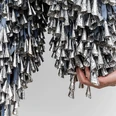 Marie Watt, Thirteen Moons, 2025 Hand holds tightly bundled silver metal cones hanging from fabric ribbons.