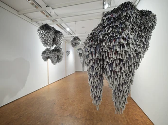 Installationsansicht HIER UND JETZT im Museum Ludwig. De/Collecting Memories Museum Ludwig, Köln 2026 Hängende Skulpturen aus dicht gefalteten Papierformen in einem weißen Galerieraum.